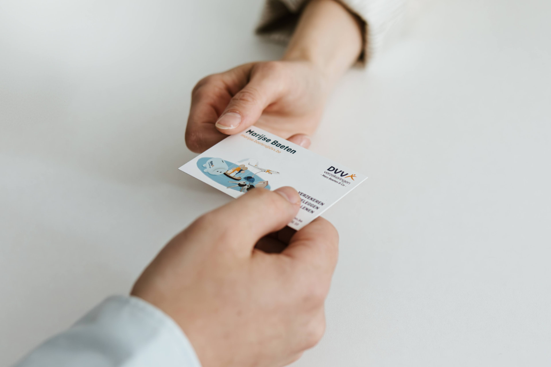 Consulent overhandigt een visitekaartje van DVV Marc Baeten & Co aan een klant