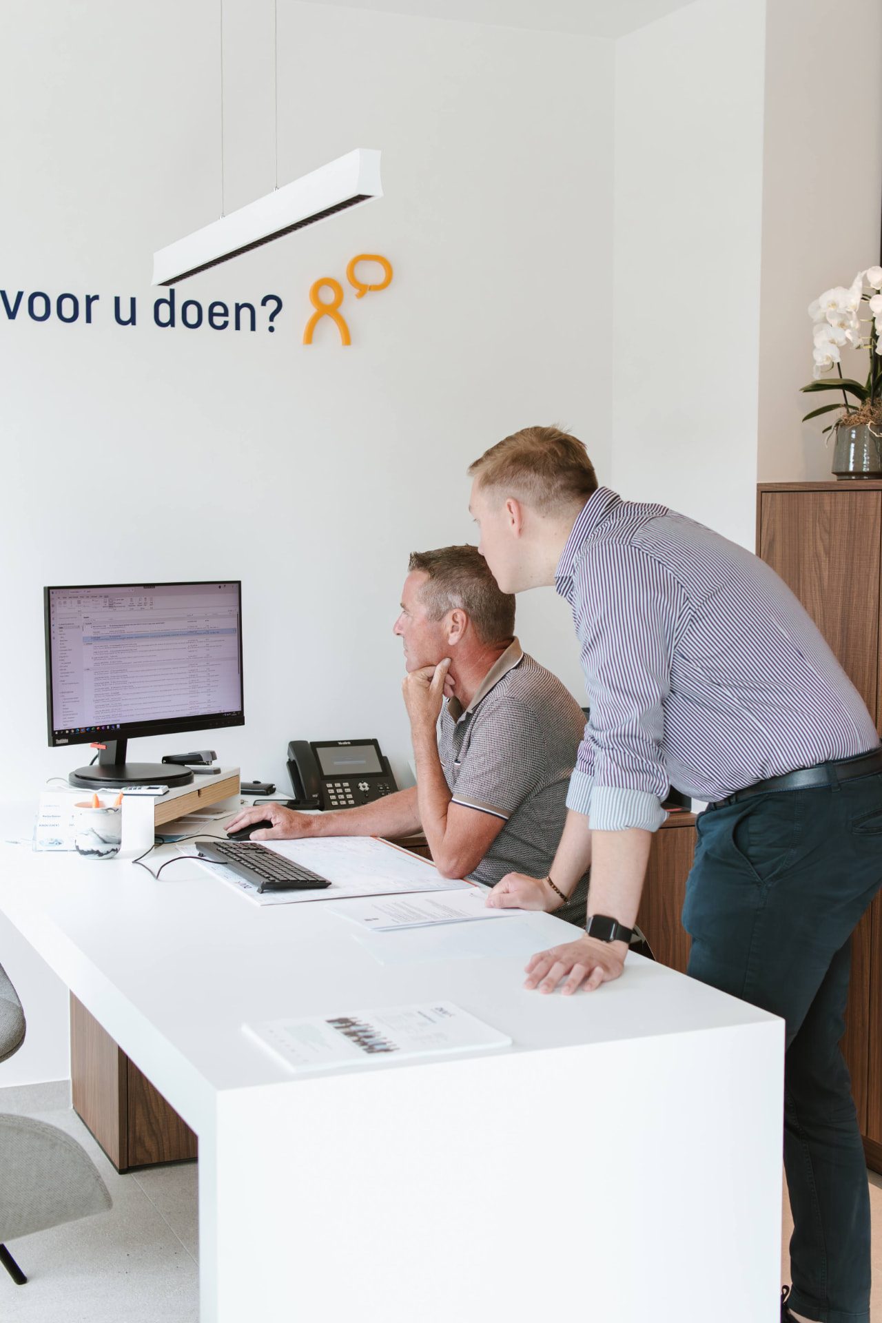 Twee consulenten bekijken samen een kredietdossier op het scherm in het kantoor